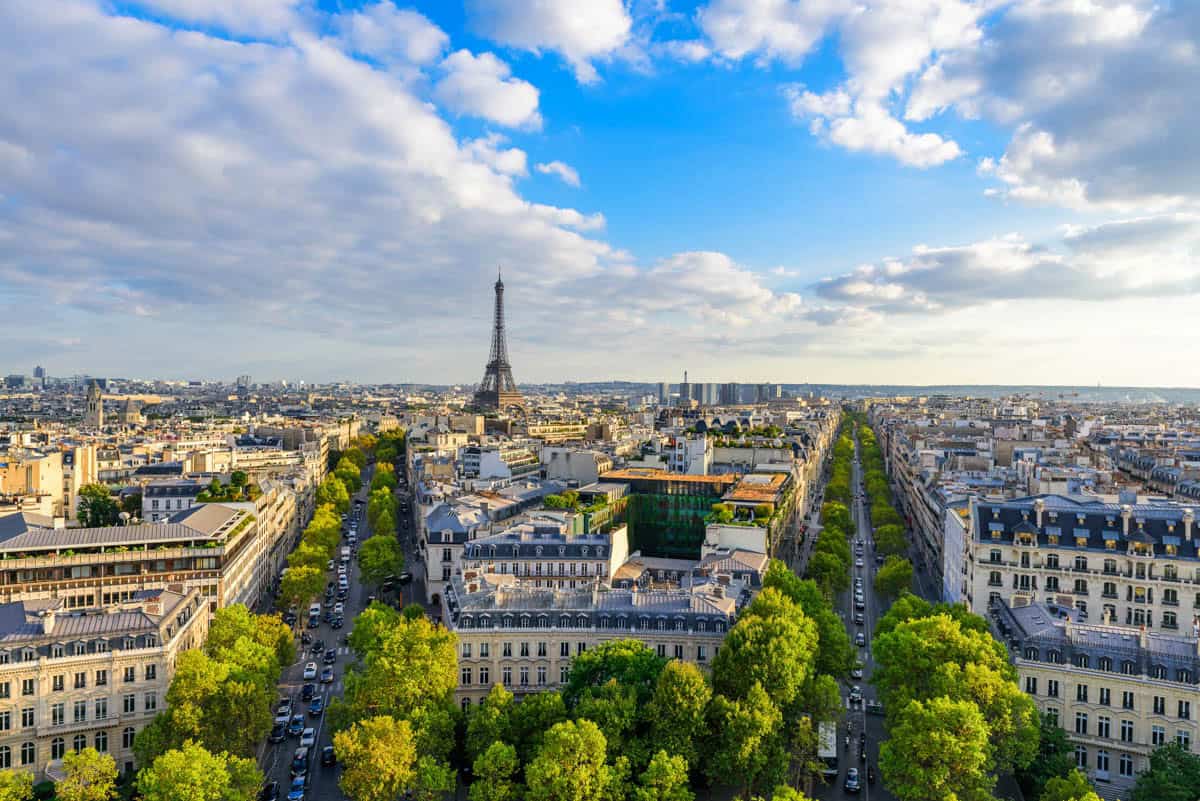Arc de Triomphe in Paris, France pairs Paris avenue grid and rooftops with the Eiffel Tower on the horizon with cityscape details.