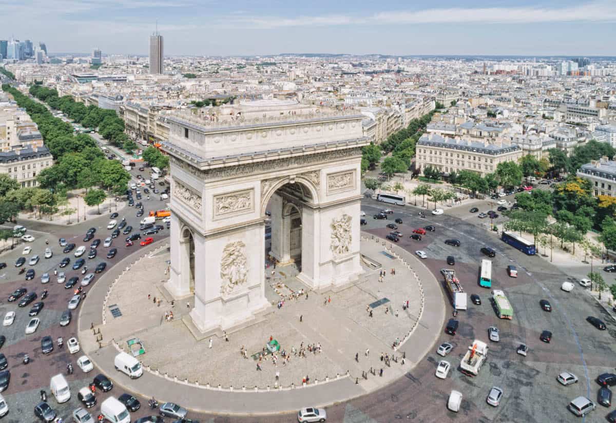 Arc de Triomphe and its circular traffic pattern seen from above with architecture details around Arc de Triomphe in Paris, France.