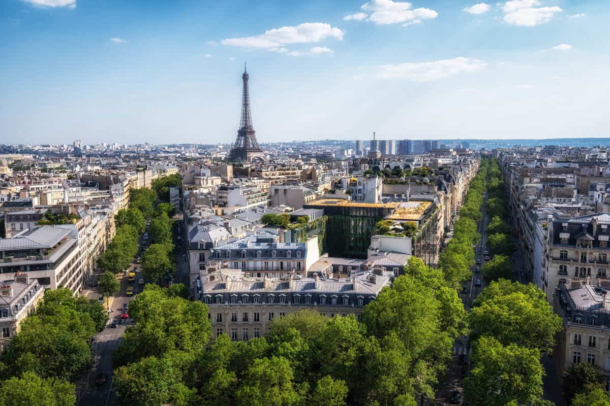 Arc de Triomphe in Paris, France pairs Paris rooftops and avenues with the Eiffel Tower in the distance with cityscape details.