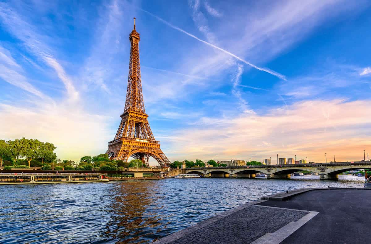 Eiffel Tower across the Seine beneath blue-and-pink evening clouds — Eiffel Tower, Paris, France.