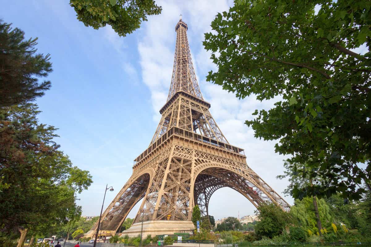Eiffel Tower seen from below through mature green trees — Eiffel Tower, Paris, France.