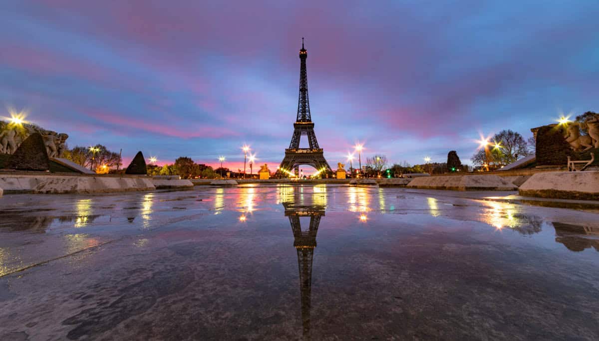 Eiffel Tower and city lights reflected on the wet Trocadéro plaza — Eiffel Tower, Paris, France.