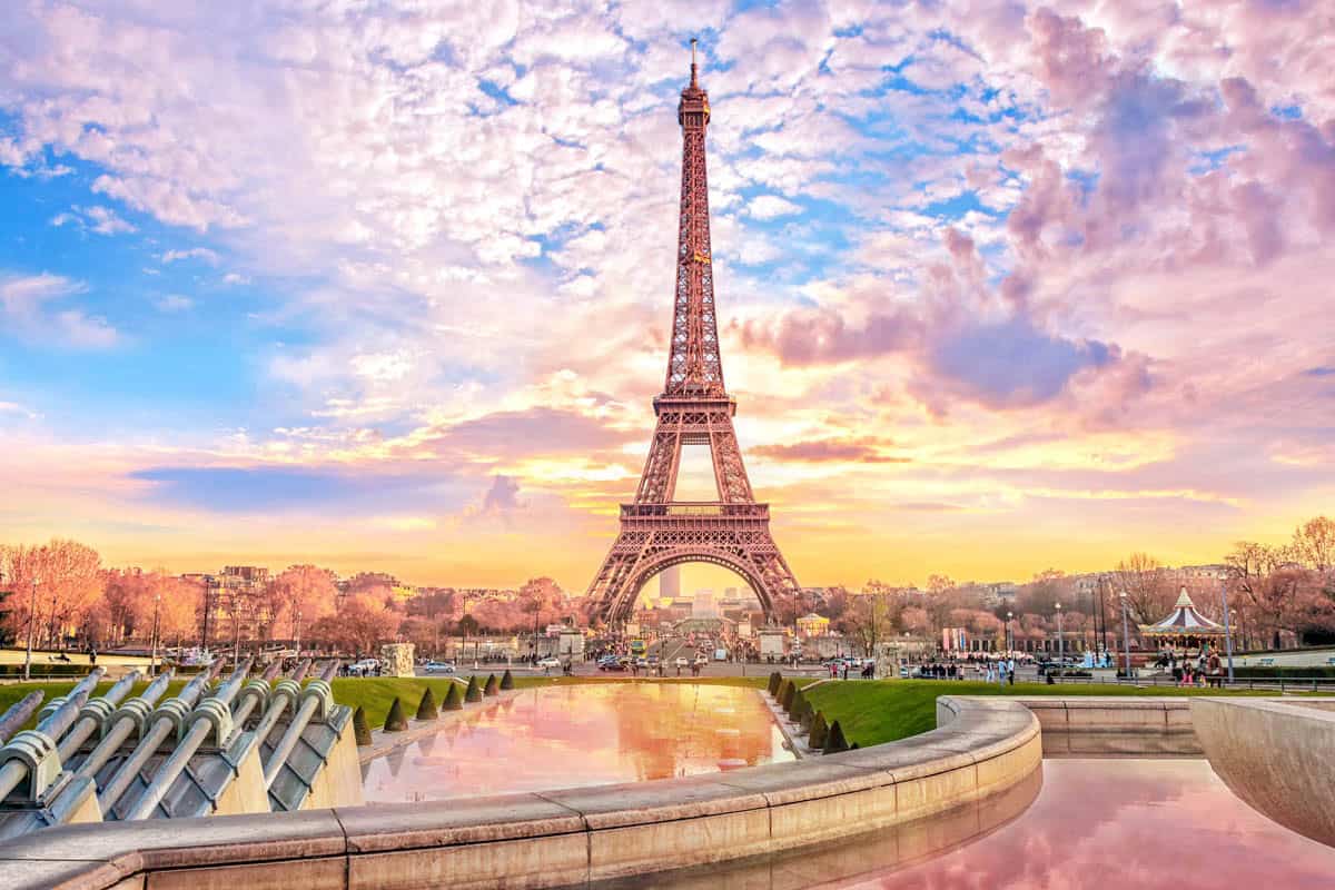 Eiffel Tower beyond the Trocadéro fountains under a pastel sky — Eiffel Tower, Paris, France.