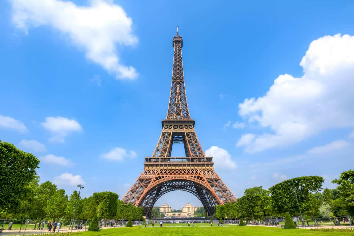 Eiffel Tower set across the green lawns of the Champ de Mars framed by tower and Paris monument at Eiffel Tower in Paris, France.