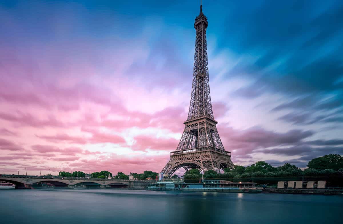 Eiffel Tower across calm water under a pink twilight sky — Eiffel Tower, Paris, France.