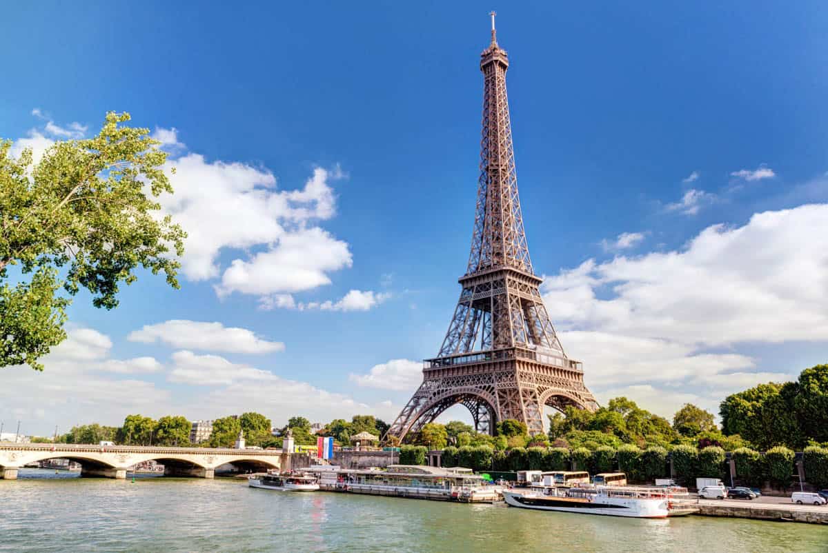 Eiffel Tower rising beyond the Seine and a low bridge — Eiffel Tower, Paris, France.