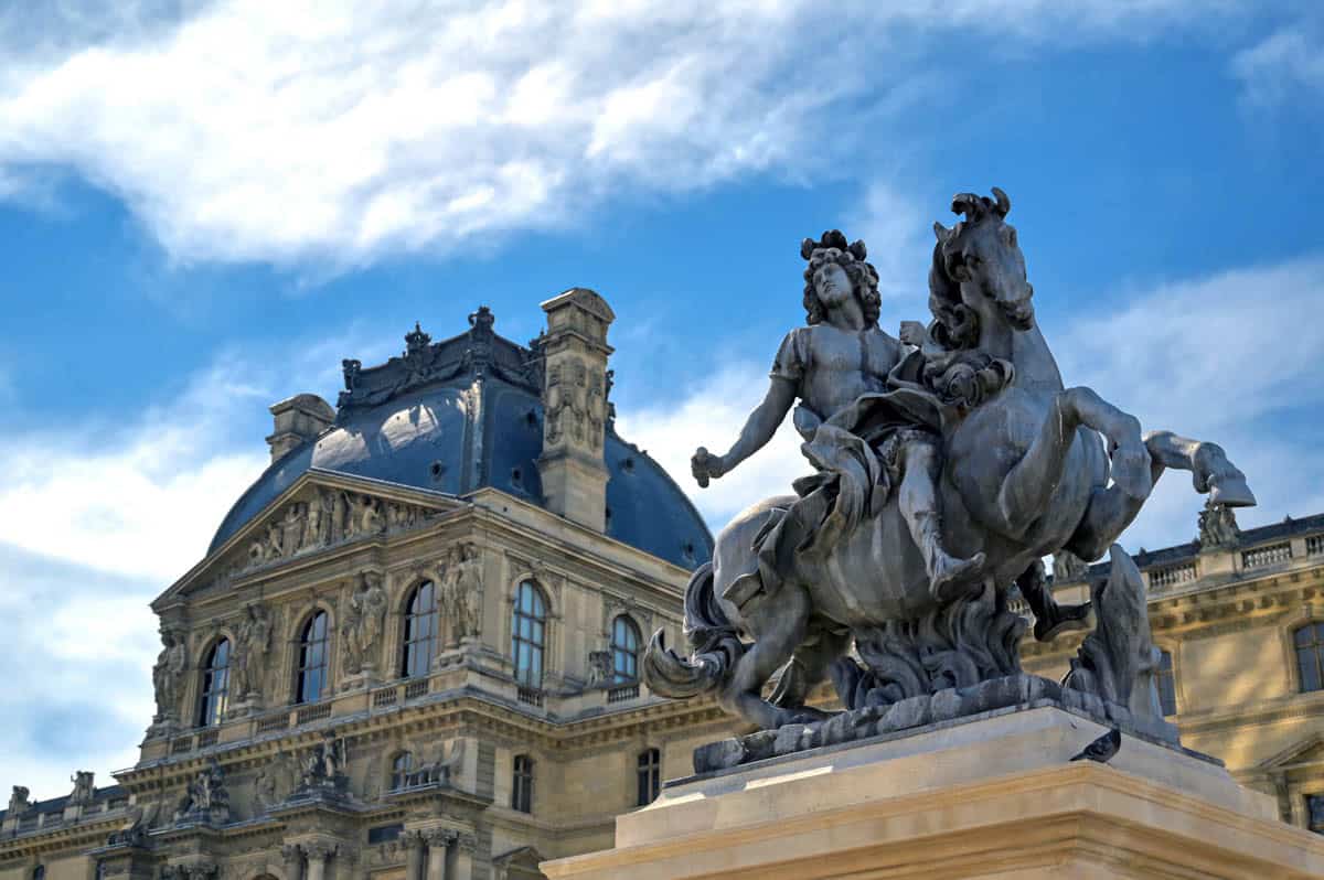 Louvre Museum in Paris, France, with equestrian sculpture and ornate Louvre palace façades.