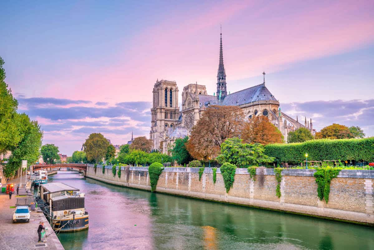 Notre-Dame Cathedral in Paris, France, featuring Notre-Dame apse beside a narrow Seine channel and sightseeing boat beside cathedral features.