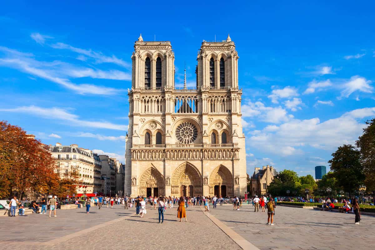 Notre-Dame west façade across a busy daylight plaza framed by cathedral and gothic architecture at Notre-Dame Cathedral in Paris, France.