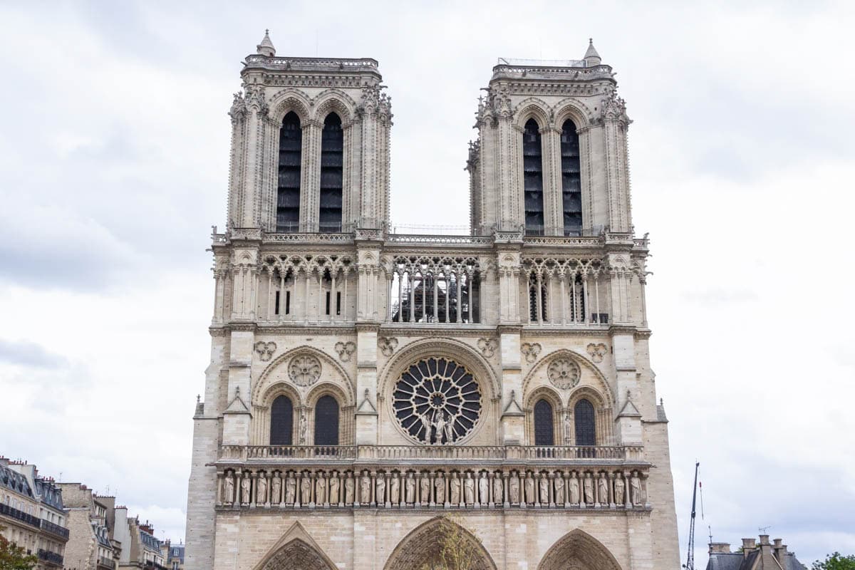 Notre-Dame Cathedral in Paris, France, with Notre-Dame west façade and rose window beneath an overcast sky.