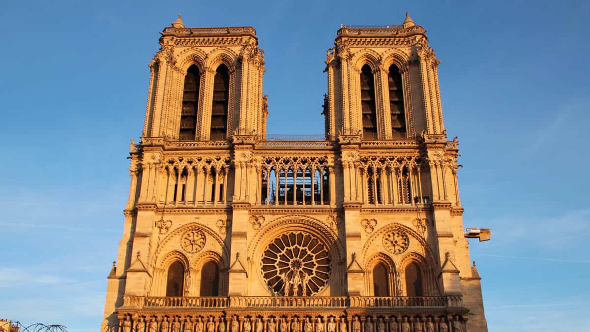 Notre-Dame Cathedral in Paris, France, with upper towers and rose window warmed by golden light.