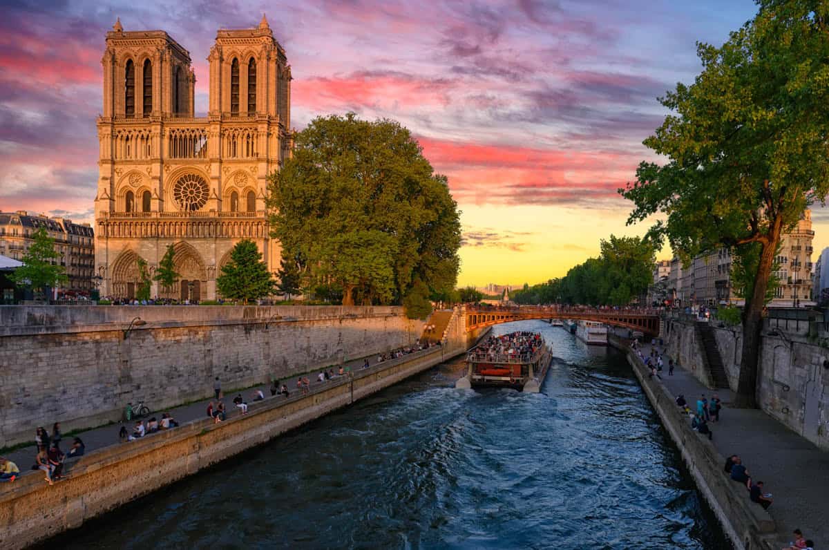 Notre-Dame beside the Seine with a riverboat at sunset — Notre-Dame Cathedral, Paris, France.
