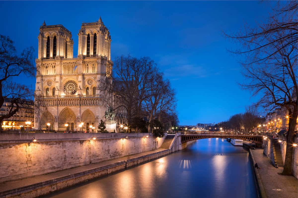 Notre-Dame and riverside buildings beneath a pink evening sky with gothic architecture details around Notre-Dame Cathedral in Paris, France.