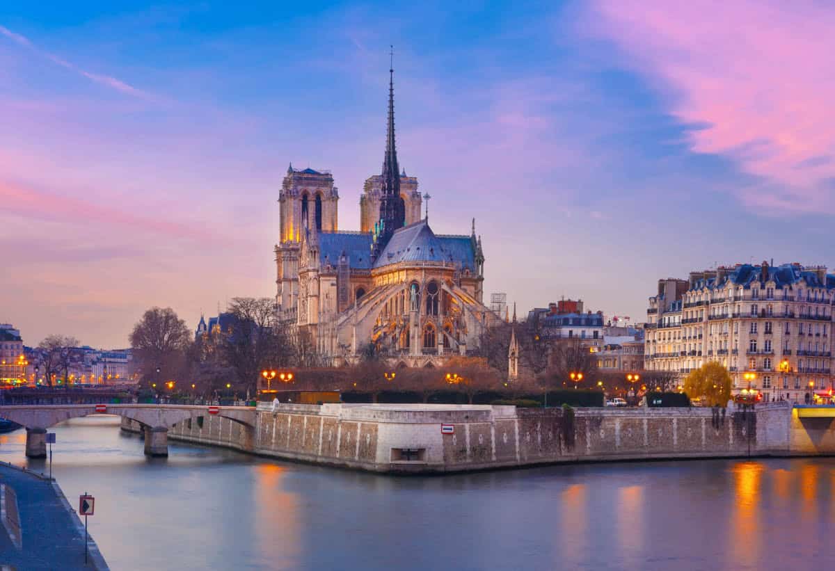 Notre-Dame apse and riverfront reflected in the Seine at dusk alongside cathedral details at Notre-Dame Cathedral in Paris, France.