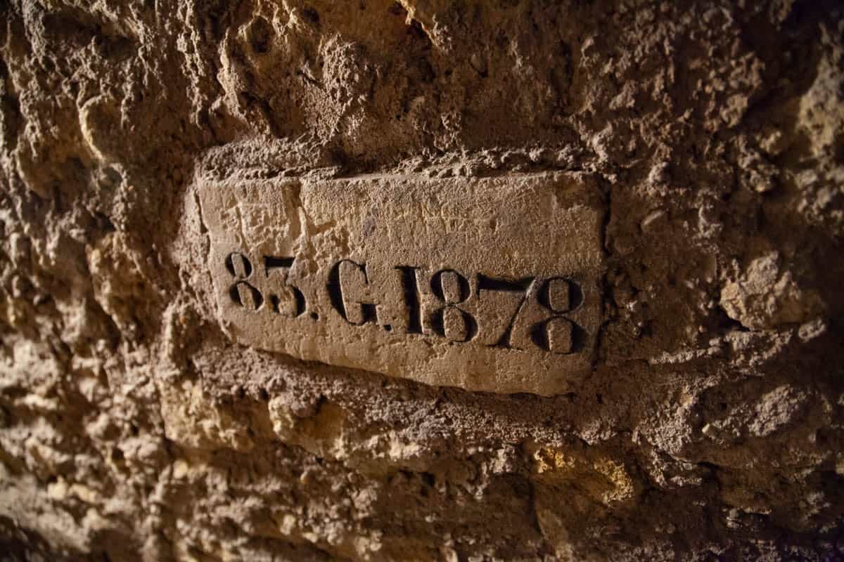 Paris Catacombs in Paris, France, with carved 1878 date marker set into a rough underground stone wall.