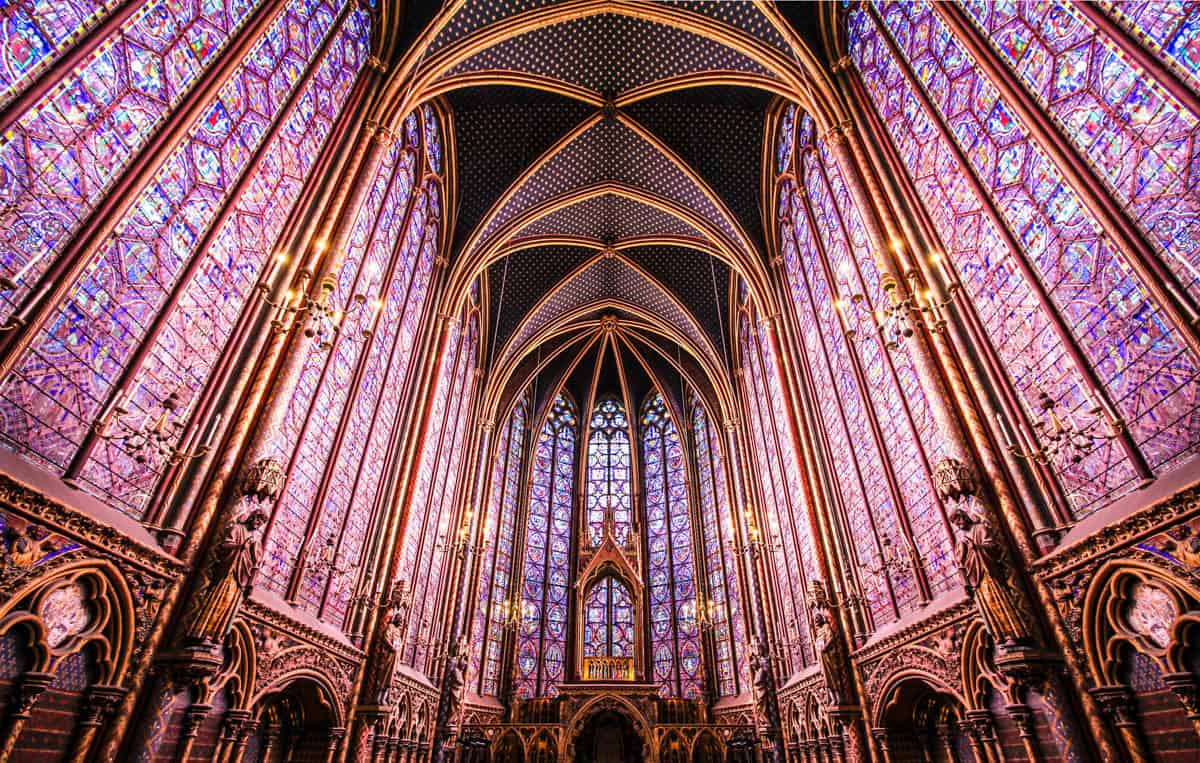 Sainte-Chapelle in Paris, France, featuring tall stained-glass walls meeting beneath a pointed painted vault beside stained glass features.