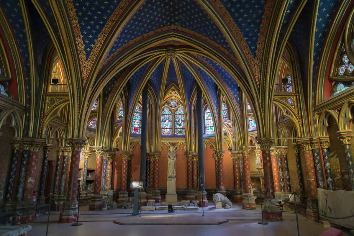 Lower chapel interior with painted vaults, columns, and windows with gothic chapel details around Sainte-Chapelle in Paris, France.