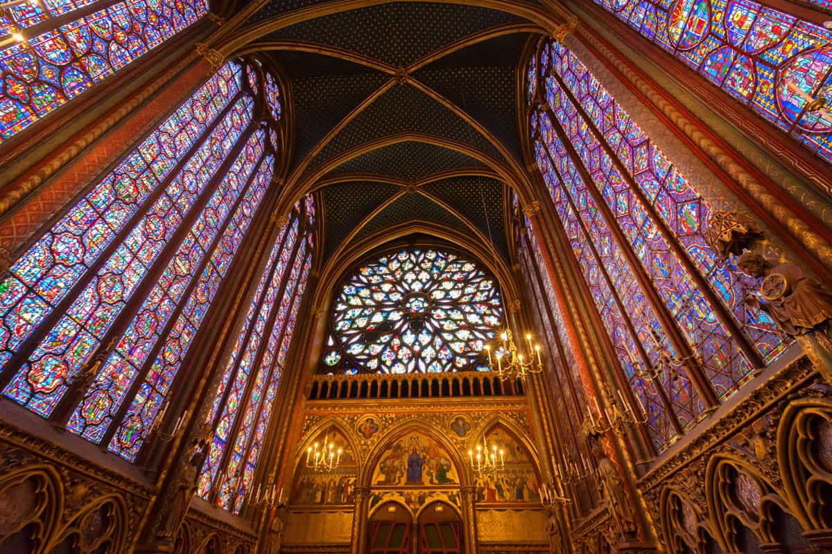 Sainte-Chapelle in Paris, France, featuring upper chapel apse beneath stained glass and a painted ribbed ceiling beside stained glass features.