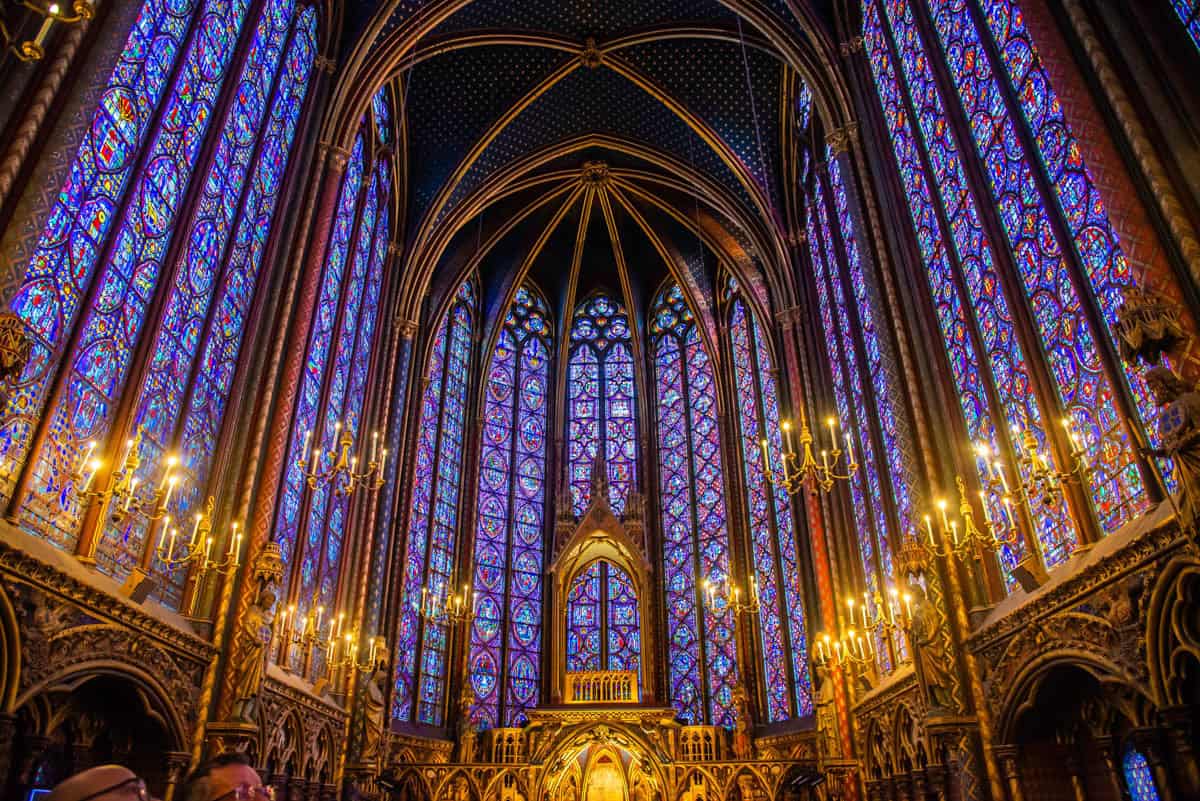 Sainte-Chapelle in Paris, France, featuring upper chapel nave filled with stained glass and gilded ornament beside stained glass features.