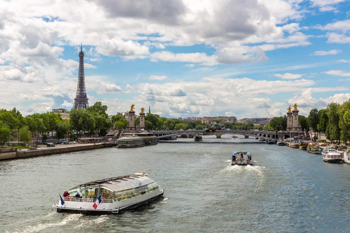 Passenger boat in the broad Seine channel with the Eiffel Tower beyond — Seine River, Paris, France.