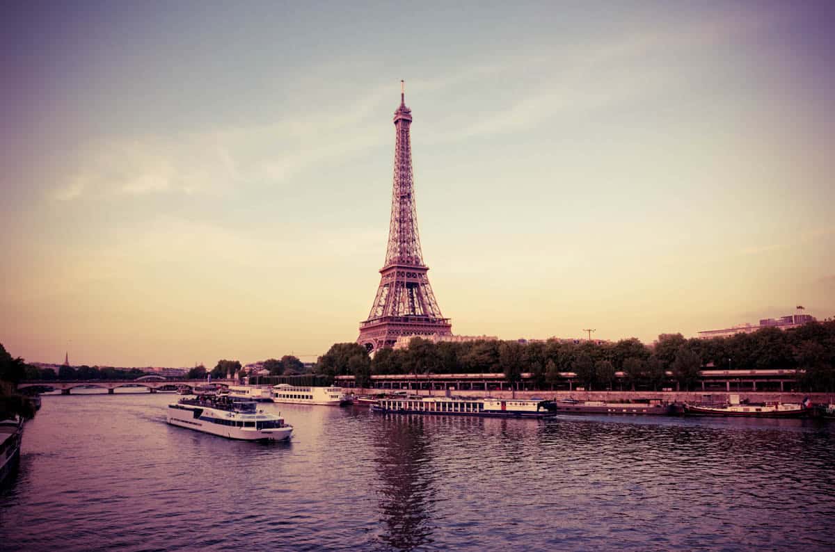 Eiffel Tower and small boats across the Seine in soft evening light beside river features within Seine River in Paris, France.