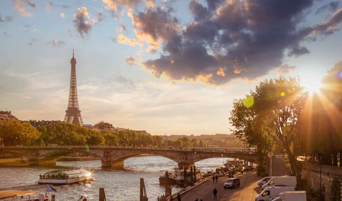Seine River in Paris, France pairs Eiffel Tower beyond Seine bridges and riverside trees at sunset with river details.