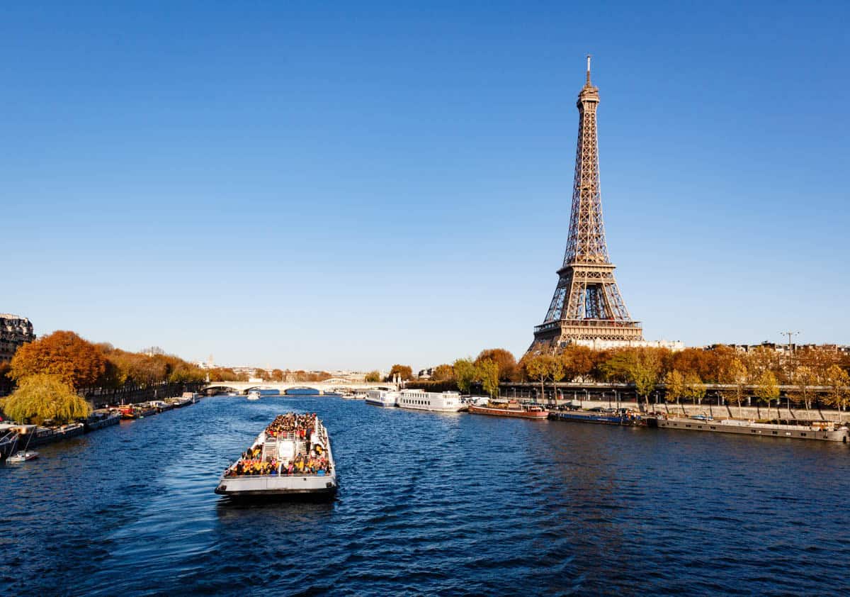 Seine River in Paris, France pairs passenger cruise boat approaching the Eiffel Tower on open water with river details.