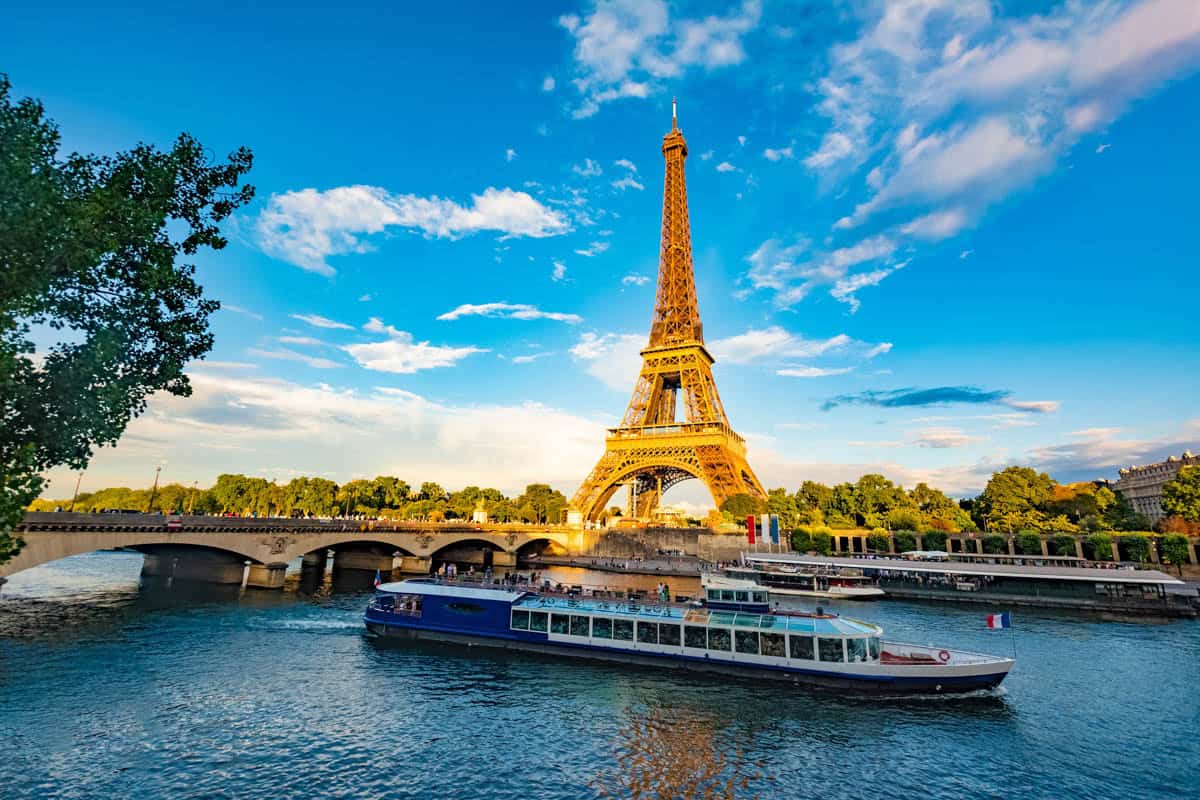 Sightseeing boat crossing the Seine below the Eiffel Tower beside cruise elements and river details at Seine River in Paris, France.