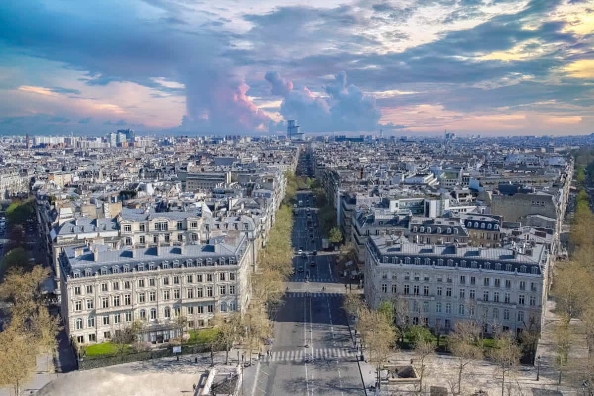 Arc de Triomphe in Paris, France pairs broad Paris avenue and rooftops receding toward the horizon with cityscape details.