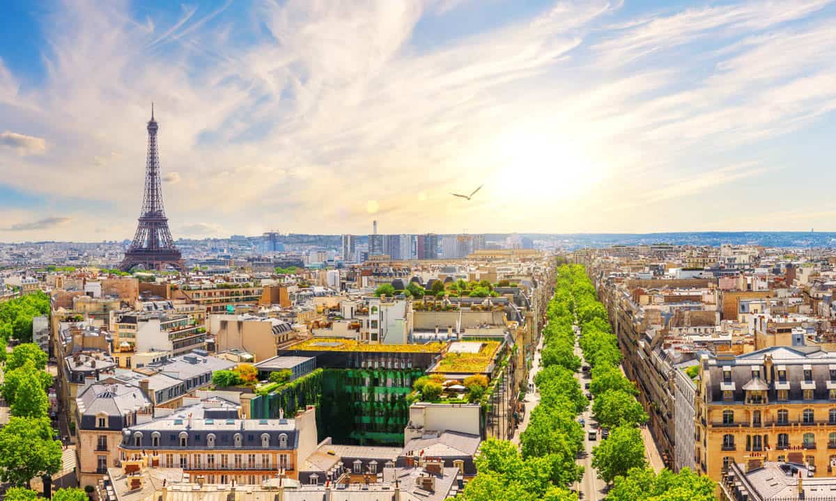 Arc de Triomphe in Paris, France pairs Eiffel Tower rising beyond dense Paris rooftops and avenues with cityscape details.